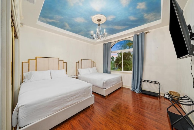 bedroom with dark wood-type flooring, a raised ceiling, and a notable chandelier