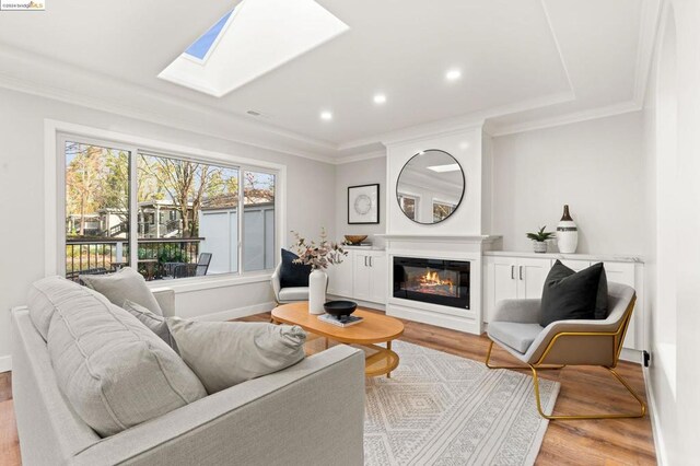 living room with light hardwood / wood-style floors, crown molding, and a skylight