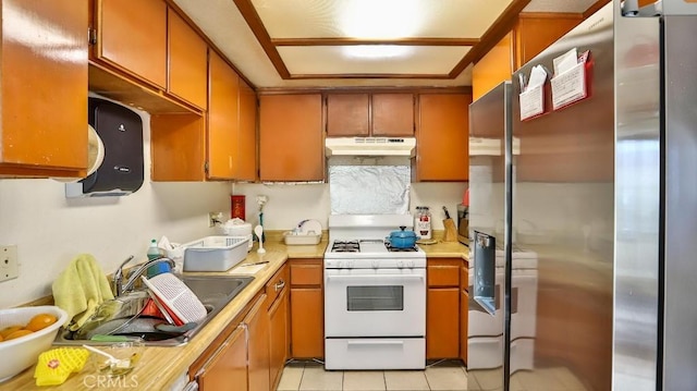 kitchen with sink, light tile patterned floors, stainless steel fridge, and white gas range oven