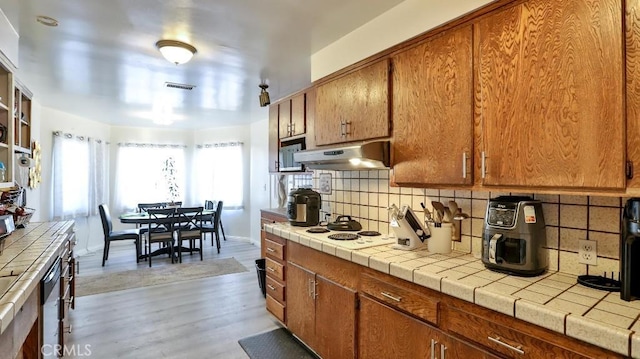 kitchen featuring light hardwood / wood-style floors, white gas cooktop, tile counters, and tasteful backsplash