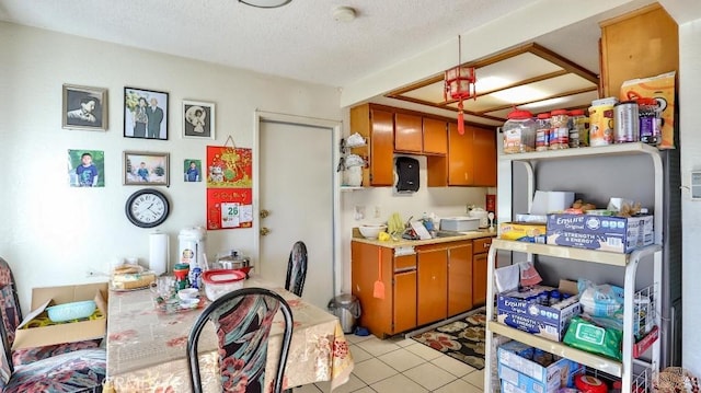 kitchen with a textured ceiling, light tile patterned flooring, and pendant lighting