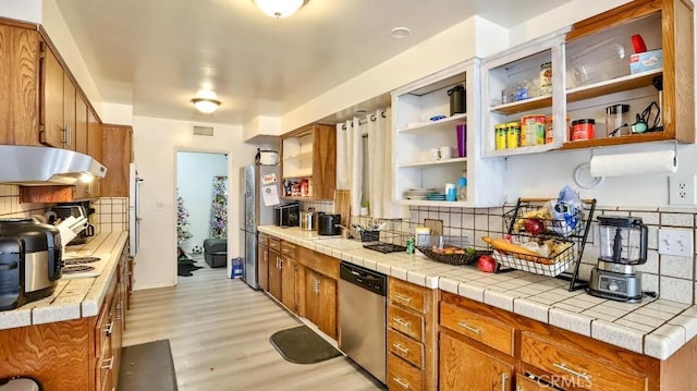 kitchen with tile counters, decorative backsplash, dishwasher, and light hardwood / wood-style floors