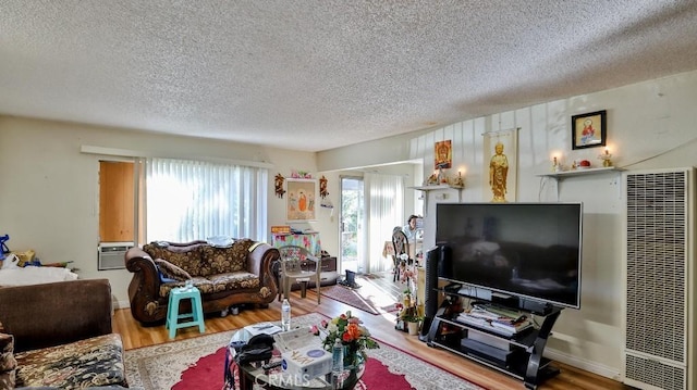 living room with a healthy amount of sunlight, wood walls, a textured ceiling, and hardwood / wood-style floors