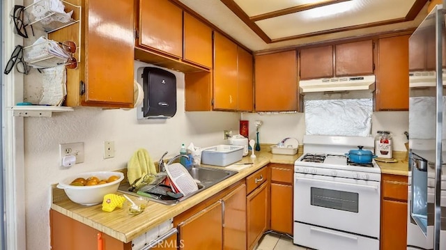 kitchen with stainless steel refrigerator with ice dispenser, light tile patterned floors, white range with gas cooktop, and sink