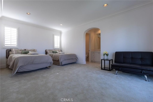 bedroom featuring ensuite bathroom, ornamental molding, and carpet flooring