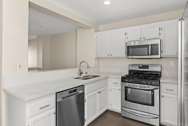 kitchen with kitchen peninsula, sink, white cabinetry, light stone countertops, and stainless steel appliances