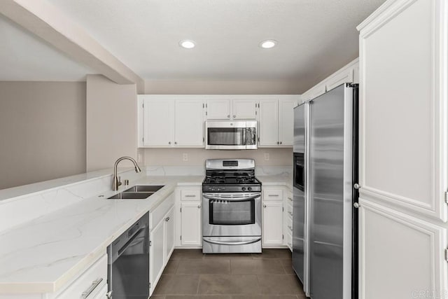 kitchen with appliances with stainless steel finishes, white cabinetry, sink, kitchen peninsula, and light stone counters