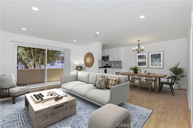 living room with light hardwood / wood-style floors and an inviting chandelier