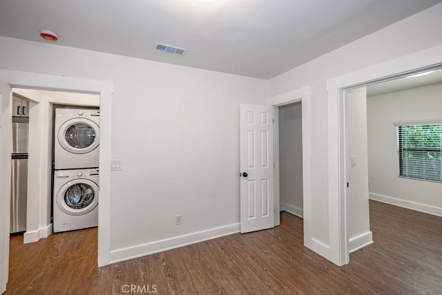 washroom with stacked washer / drying machine and dark hardwood / wood-style floors