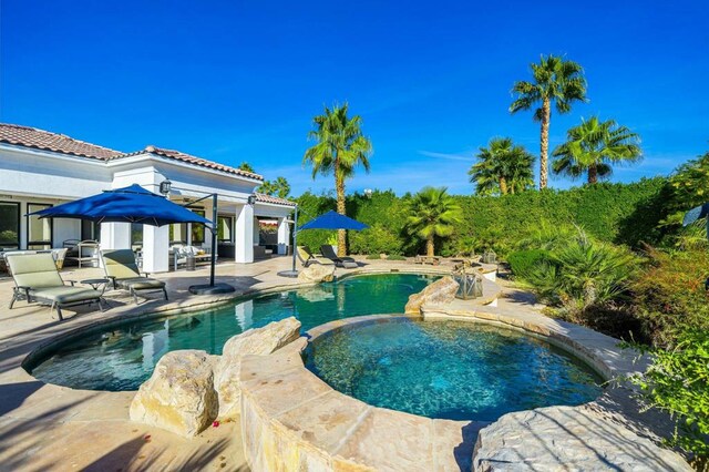 view of swimming pool featuring a patio and an in ground hot tub