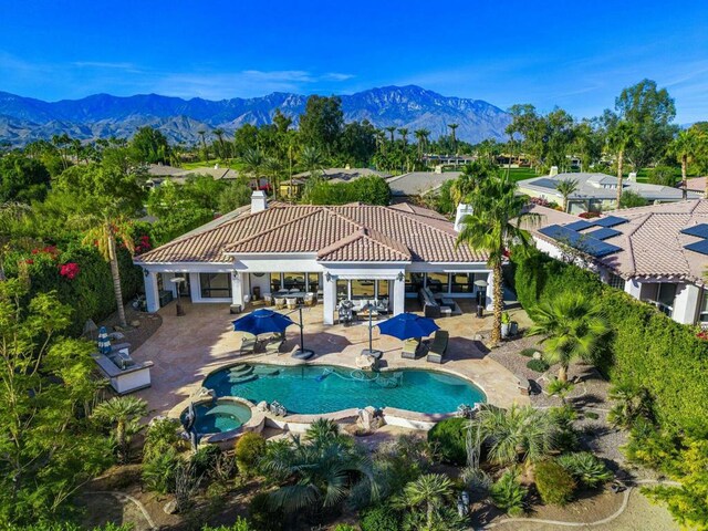 view of pool with a patio area, a mountain view, and an in ground hot tub