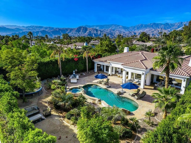 view of swimming pool with a patio area, a mountain view, and an in ground hot tub