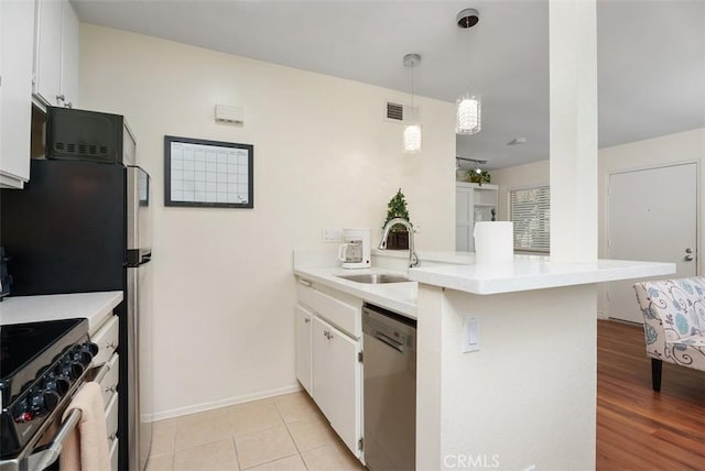 kitchen with appliances with stainless steel finishes, white cabinetry, sink, hanging light fixtures, and kitchen peninsula