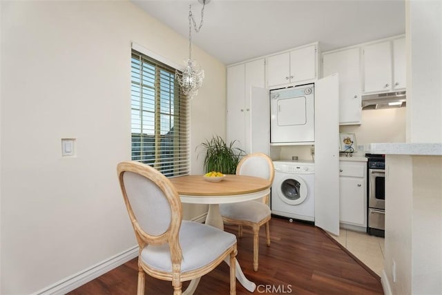 dining area featuring an inviting chandelier, stacked washer / drying machine, and hardwood / wood-style floors