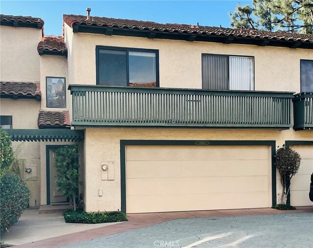 view of front of property featuring a balcony, a garage, and central air condition unit