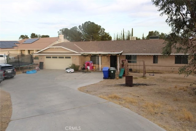 ranch-style house featuring a garage and a trampoline