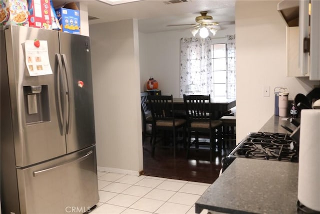 kitchen with gas range, light tile patterned floors, stainless steel fridge, ceiling fan, and white cabinets