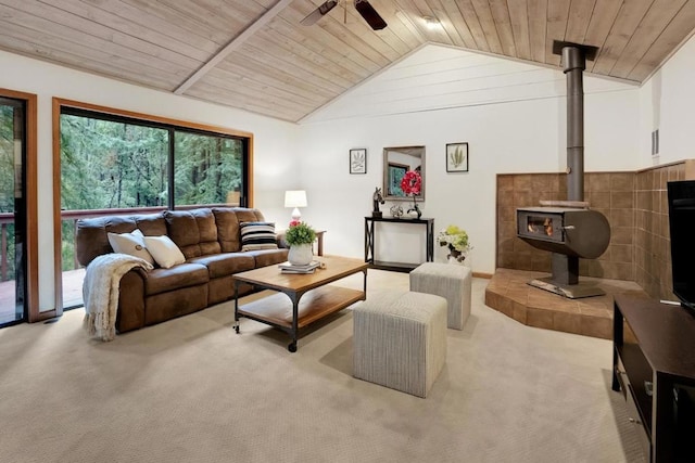 living room featuring a wood stove, light colored carpet, vaulted ceiling, ceiling fan, and wooden ceiling