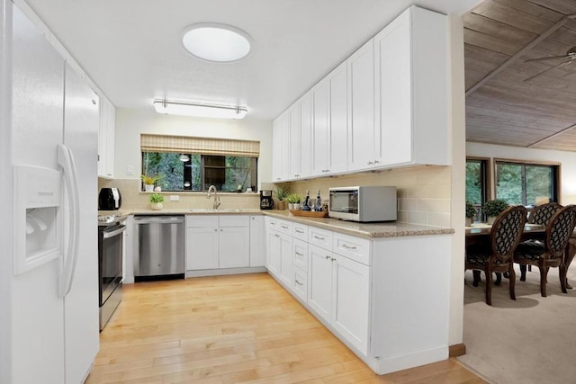 kitchen with appliances with stainless steel finishes, white cabinetry, tasteful backsplash, and sink