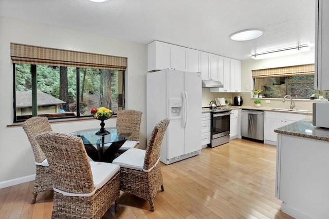 kitchen with backsplash, light hardwood / wood-style floors, sink, appliances with stainless steel finishes, and white cabinets