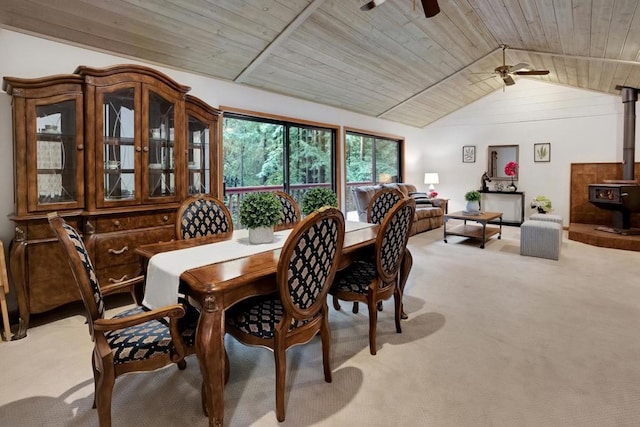 carpeted dining space featuring vaulted ceiling, ceiling fan, wood ceiling, and a wood stove