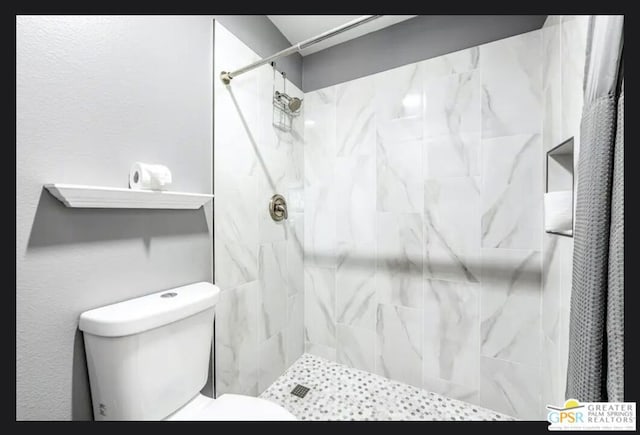 bathroom featuring toilet and a tile shower