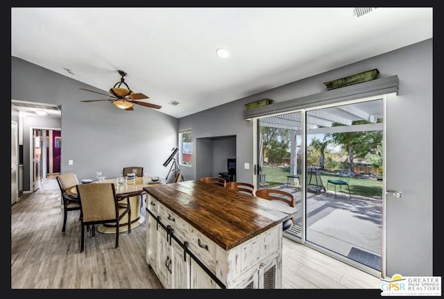 dining room with ceiling fan, vaulted ceiling, and light hardwood / wood-style floors