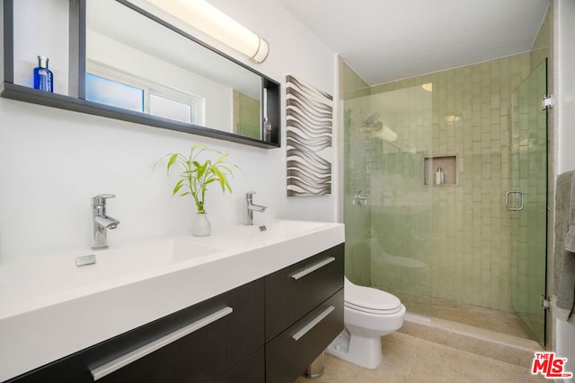 bathroom featuring vanity, toilet, and a shower with shower door