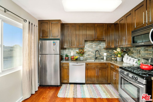 kitchen featuring wood-type flooring, sink, appliances with stainless steel finishes, and tasteful backsplash