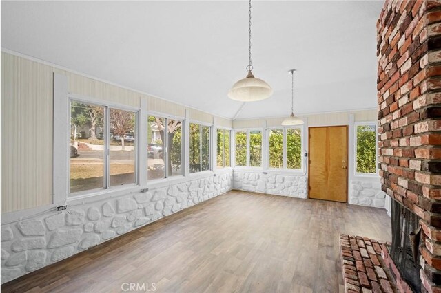 unfurnished sunroom with a brick fireplace and lofted ceiling