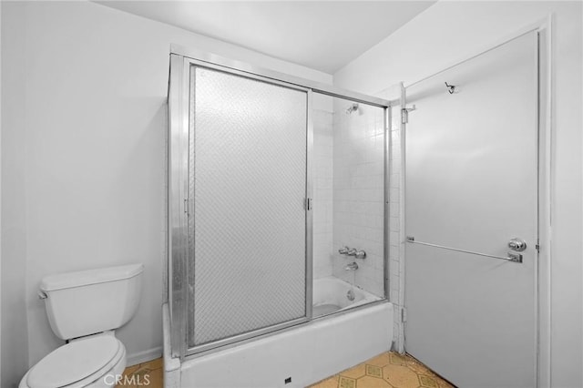 bathroom with toilet and combined bath / shower with glass door