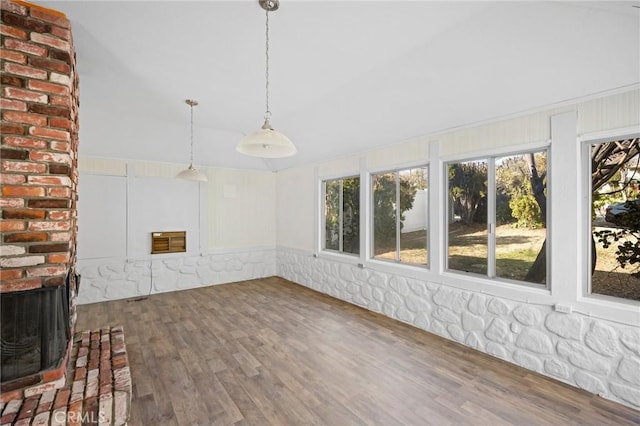 unfurnished sunroom with a brick fireplace, heating unit, and lofted ceiling