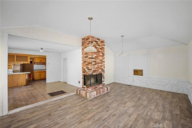 unfurnished living room with a brick fireplace, hardwood / wood-style flooring, and lofted ceiling