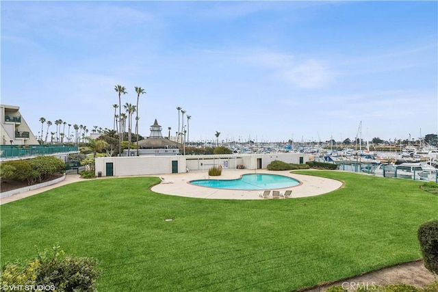 view of swimming pool with a yard and a water view