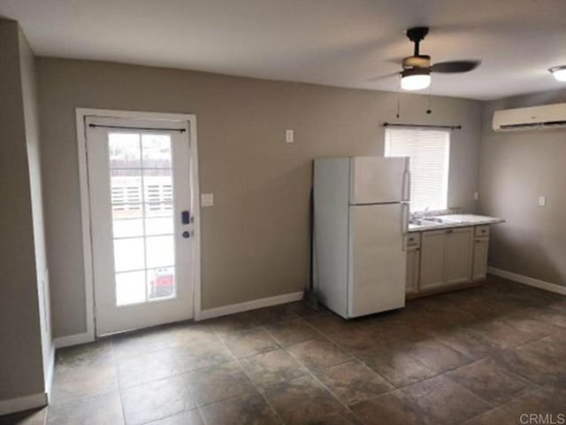 kitchen with white fridge, ceiling fan, a wall unit AC, and sink