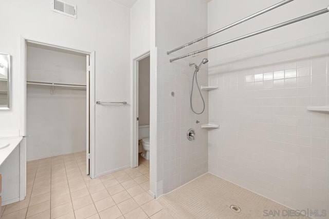 bathroom featuring tiled shower, tile patterned floors, and toilet