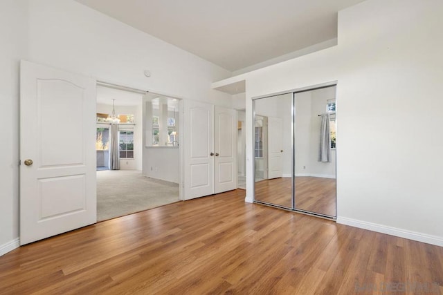 unfurnished bedroom featuring light hardwood / wood-style flooring and a notable chandelier