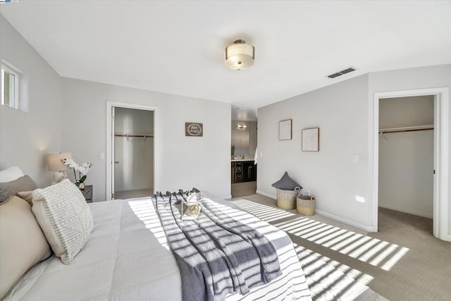 carpeted bedroom with a walk in closet and ensuite bath