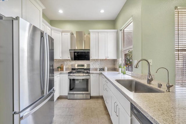 kitchen featuring appliances with stainless steel finishes, white cabinetry, wall chimney exhaust hood, and sink