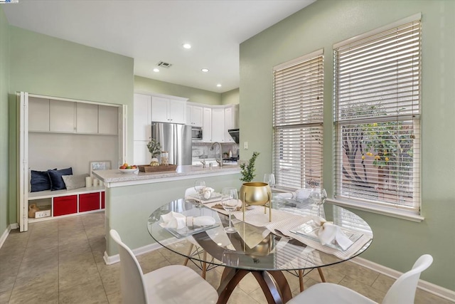 dining area featuring sink and light tile patterned flooring