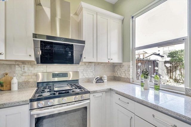 kitchen featuring backsplash, white cabinets, wall chimney exhaust hood, and stainless steel range with gas cooktop