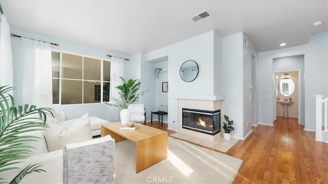 living room featuring light hardwood / wood-style floors and a tiled fireplace