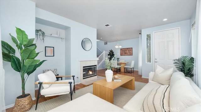 living room with light hardwood / wood-style floors, a notable chandelier, and a fireplace