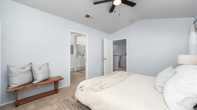 bedroom featuring ceiling fan, ensuite bath, light colored carpet, and lofted ceiling