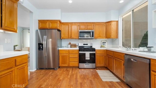 kitchen with a wealth of natural light, stainless steel appliances, light hardwood / wood-style floors, and sink