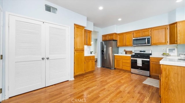 kitchen featuring light hardwood / wood-style floors, appliances with stainless steel finishes, and tasteful backsplash