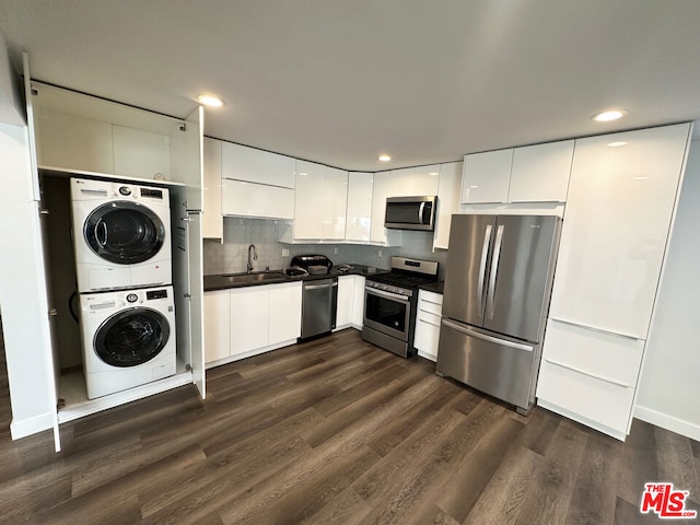 kitchen featuring stacked washer and dryer, white cabinetry, stainless steel appliances, dark wood-type flooring, and sink