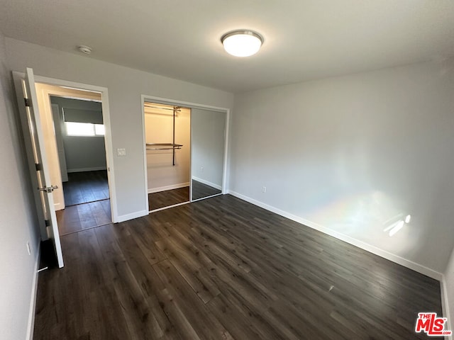 unfurnished bedroom with dark hardwood / wood-style floors and a closet