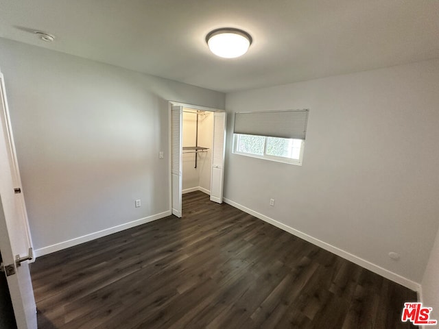 unfurnished bedroom featuring a closet and dark hardwood / wood-style flooring