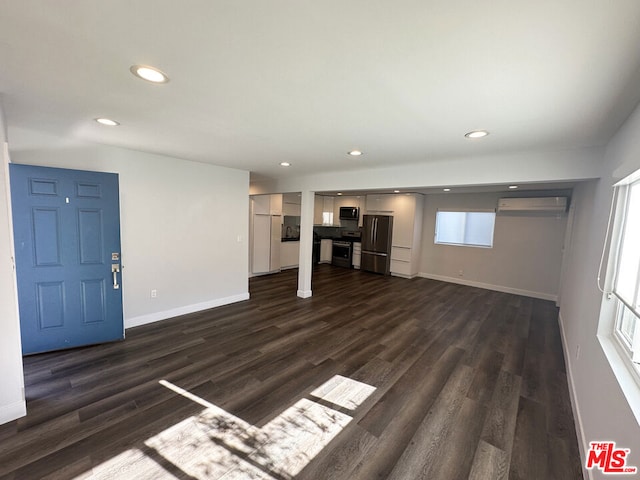 unfurnished living room featuring dark hardwood / wood-style flooring and a wall unit AC